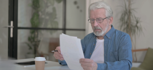 Older man reviewing documents as he learns about the military buy back process for federal retirement.